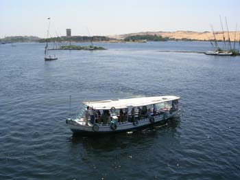 Barco navegando en Asuán con falucas y paisaje desértico