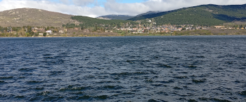 Embalse de Navacerrada con el pueblo y colinas verdes al fondo