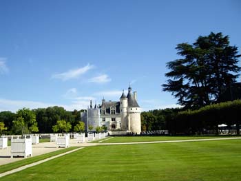 Castillo francés con jardines simétricos y árboles alineados en un día soleado
