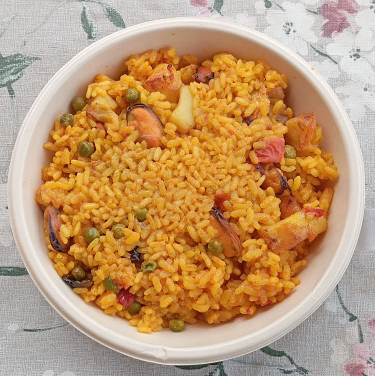 Plato de paella valenciana tradicional con arroz, pollo y verduras